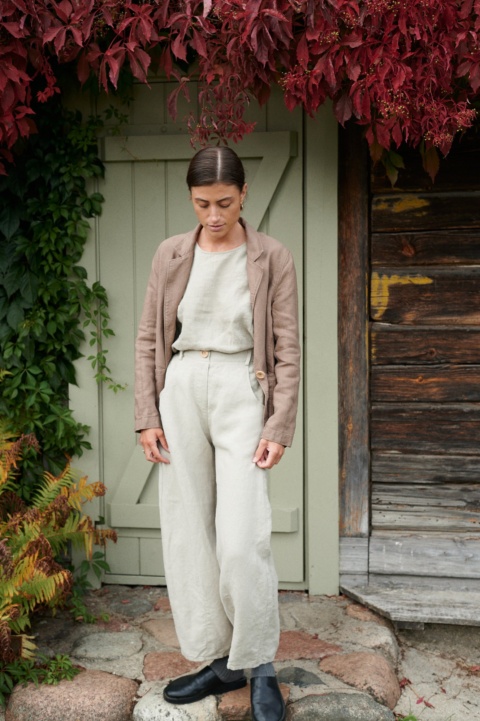 A woman standing in light grey heavy linen trousers