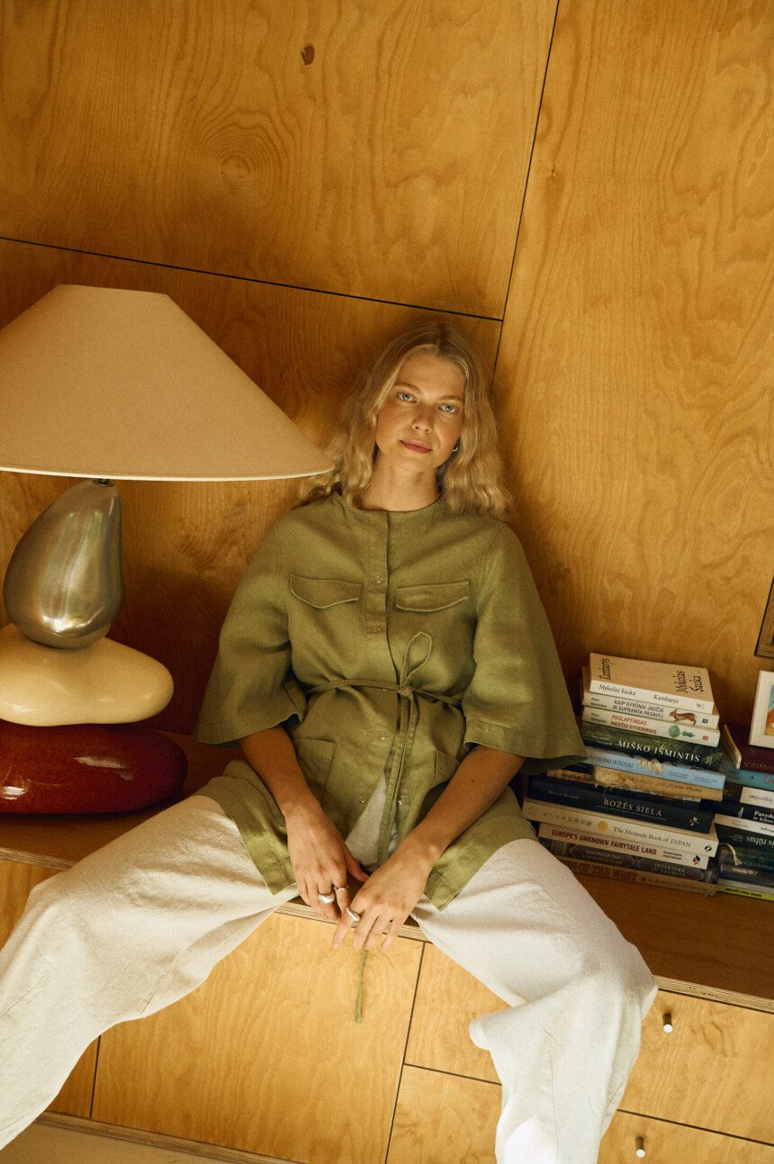 Seated model in olive linen overshirt paired with natural linen cotton trousers, relaxed full outfit